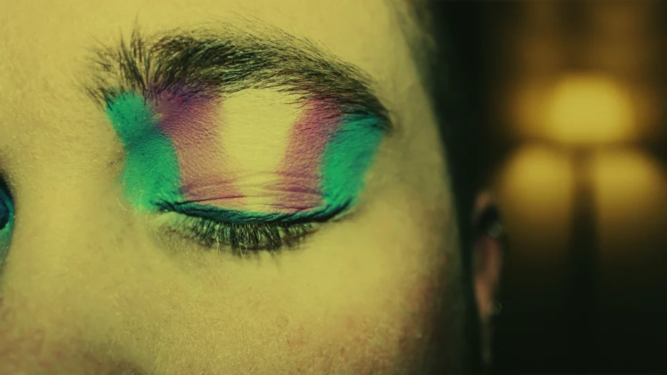 Nærbilde av et lukket øye, med øyenskygge i fargene til flagget for transkjønnede. Foto: Kyle/Unsplash